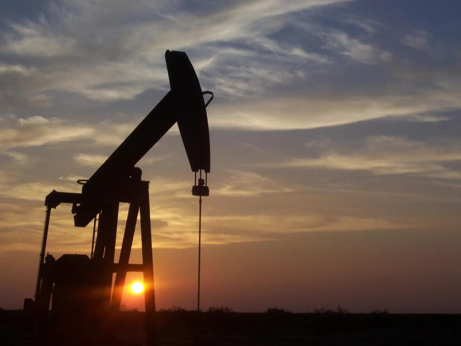 Pump jack and oilfield equipment on flat scrubland in the Permian Basin of West Texas