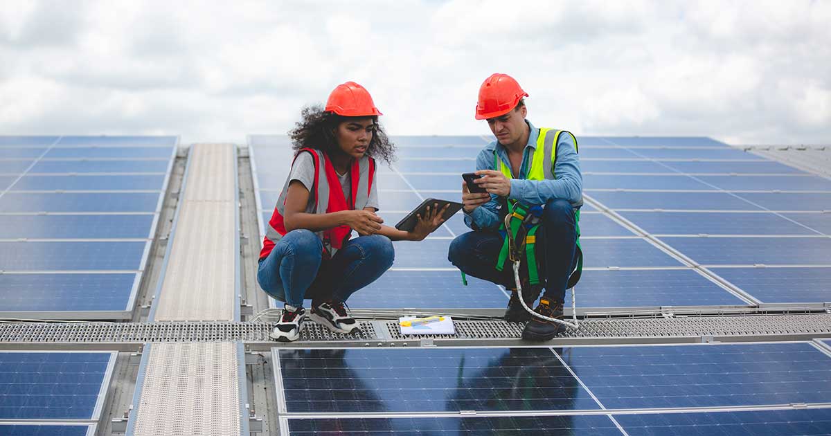 Two people shaking hands in front of rows of solar panels, representing a distributed-energy power purchase agreement.