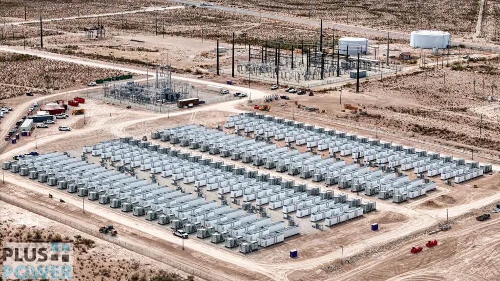 Aerial photograph of Plus Power's Rodeo Ranch battery storage site in Pecos, Texas, showing a large grid of white battery enclosures and the adjacent substation.