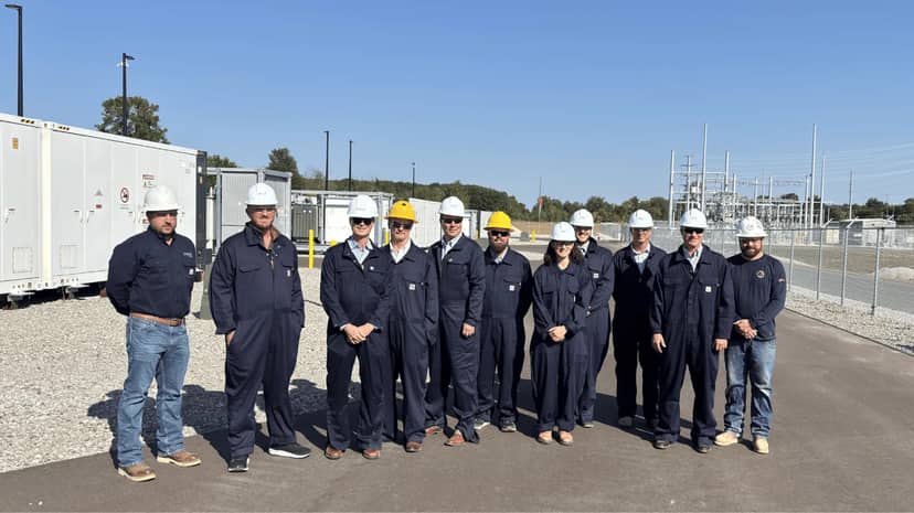 Tibbits Energy Storage battery containers and substation behind the project team at the operating facility.